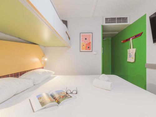 a bedroom with a bed with a book on it at greet hôtel Annecy Cran-Gevrier by Accor in Annecy