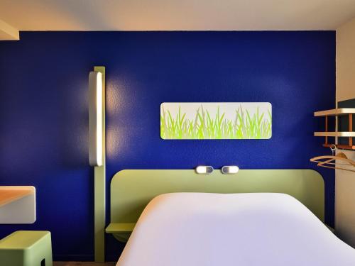 a room with a white bed and a blue wall at Ibis budget Chambéry Centre Ville in Chambéry