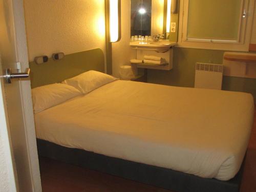 a bedroom with a large bed with a white bedspread at IBIS Budget Aix en Provence Est Le Canet in Meyreuil