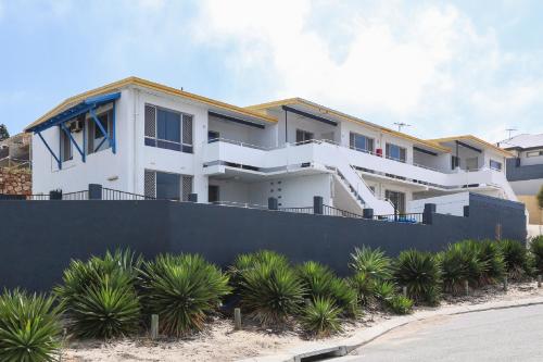 a white house with a black fence at Scarborough Apartments in Perth