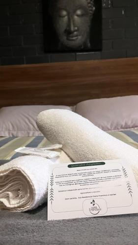 a bed with a towel and a piece of paper on it at Pousada Dona Francisca in Florianópolis