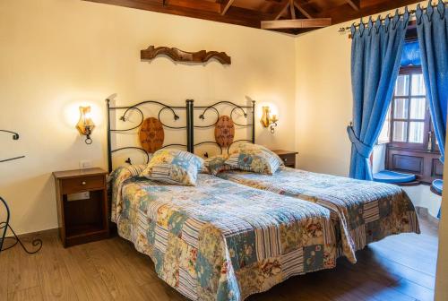 a bedroom with a large bed with blue curtains at Casa Rural Monte del Agua in Los Silos