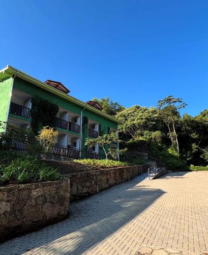 a green building with a stone wall next to a street at Pousada Dona Francisca in Florianópolis