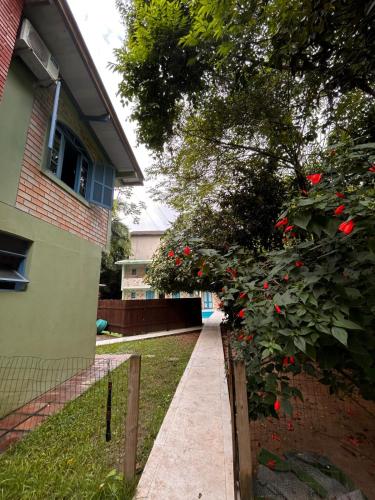 a sidewalk in front of a house with a bush with red flowers at Pousada Dona Francisca in Florianópolis