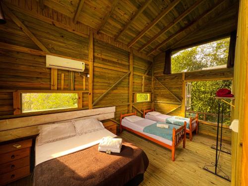 a bedroom with two beds in a log cabin at Pousada Vale da Magia in Praia do Rosa