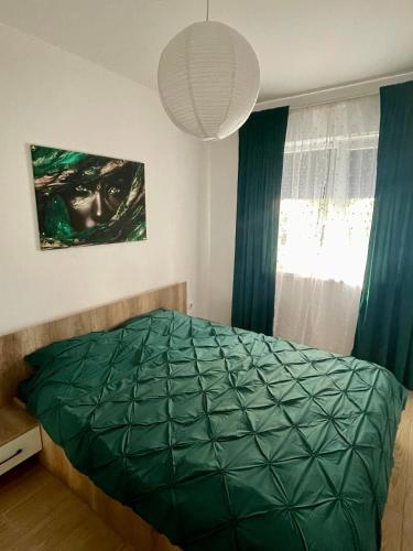 a bedroom with a green comforter on a bed at Militari Comfort Apartment in Roşu