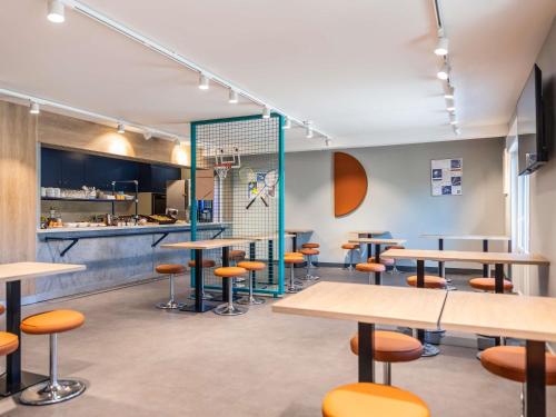 a dining room with tables and stools at Ibis Budget Villefranche in Limas