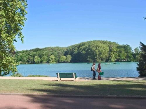 two people standing next to a bench in front of a lake at Ibis Budget Villefranche in Limas