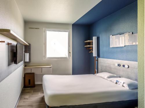a bed in a room with a blue wall at ibis budget Porte D'Orleans in Paris