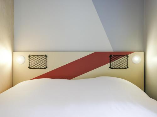 a bedroom with a white bed and two lights at ibis Budget Villemomble in Villemomble