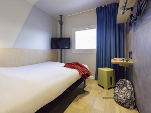 a hotel room with a bed and a window at ibis Budget Villemomble in Villemomble