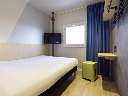 a bedroom with a white bed and a window at ibis Budget Villemomble in Villemomble
