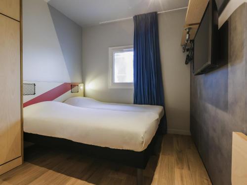 a small room with a bed and a window at ibis Budget Villemomble in Villemomble