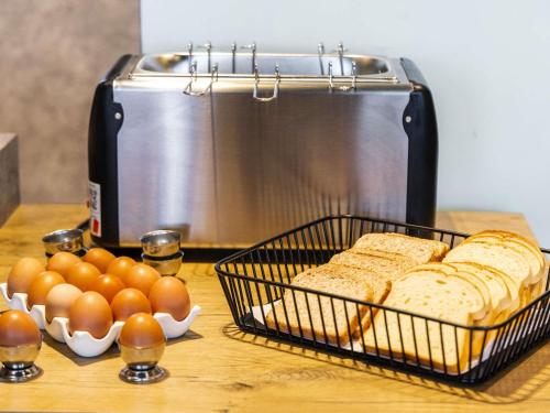 a table with bread and eggs and a toaster at ibis Budget Villemomble in Villemomble