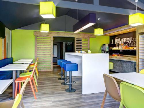 a restaurant with colorful chairs and tables and a bar at ibis budget Caen Hérouville in Hérouville-Saint-Clair