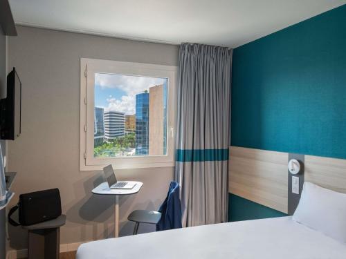 a room with a bed and a window with a laptop at ibis budget Nice Aeroport in Nice