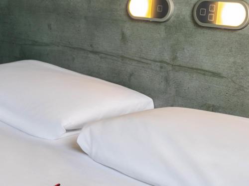 two beds in a room with clocks on the wall at ibis budget Montpellier Sud Près d'Arènes in Montpellier