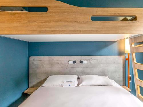 a bed in a small room with blue walls at ibis budget Montpellier Sud Près d'Arènes in Montpellier