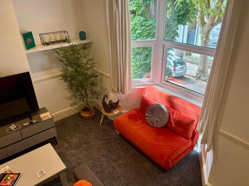 a living room with a red couch and a large window at Southend city Escape, SS1, High St and beach are steps away in Southend-on-Sea
