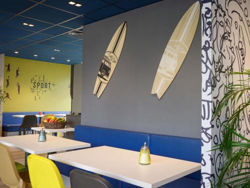 a dining room with tables and surfboards on the wall at ibis budget Toulouse Centre Gare in Toulouse