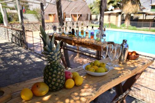 una mesa de madera con una piña y cuencos de fruta en Hotel Observatorio TukunMapu, en Vicuña