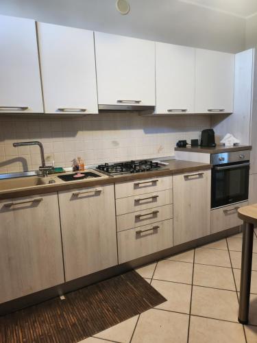 a kitchen with white cabinets and a sink and a stove at Cerano city house in Cerano