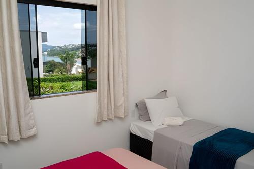 a bedroom with a bed and a window with a view at Casa com piscina vista para lago, 03 quartos confortáveis in Capitólio