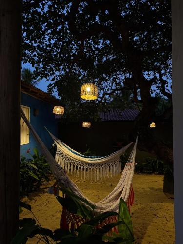 a hammock on the beach under a tree at night at Casa Peroá Pousada in Icaraí