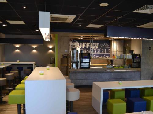 a restaurant with green and blue chairs and tables at ibis budget Paris Porte de Vanves in Vanves
