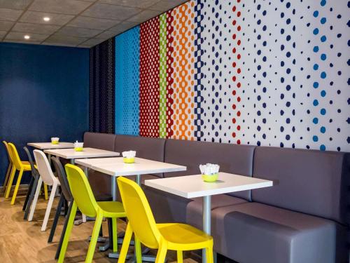 a row of tables in a restaurant with yellow chairs at ibis budget Avignon Centre in Avignon