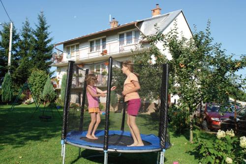 two children standing on a play structure in a yard at Noclegi Zlota Gorka in Polańczyk