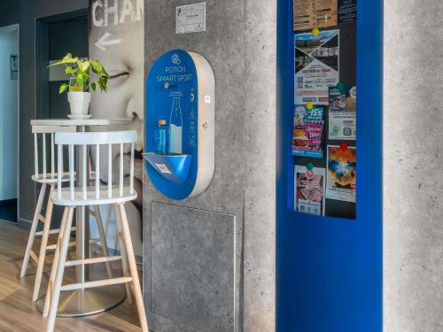 a blue and white dispenser on a wall next to a stool at ibis budget Caen Mondeville in Mondeville