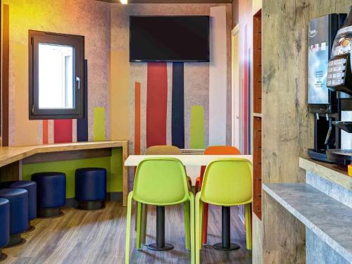 a restaurant with chairs and a table with a tv at ibis Budget Caen Memorial in Caen