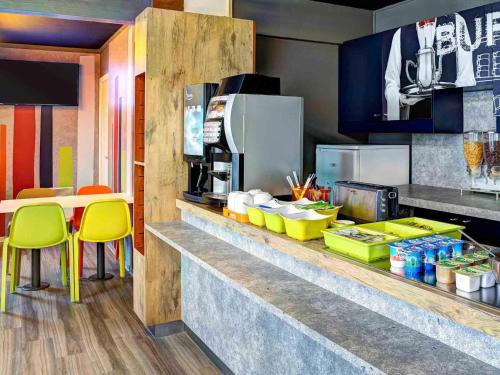a kitchen with a counter with yellow stools in a restaurant at ibis Budget Caen Memorial in Caen