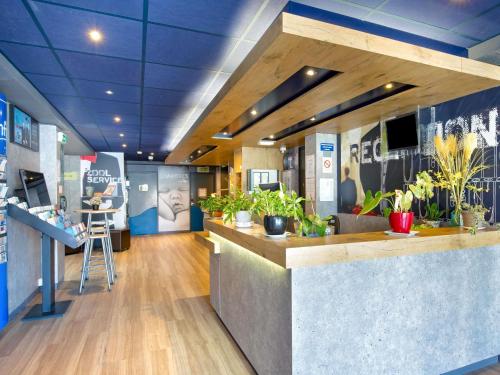 a lobby with a counter with potted plants in it at ibis budget Cavaillon in Cavaillon