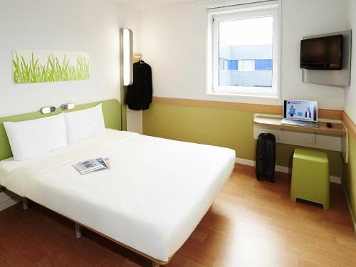 - une chambre avec un lit et un ordinateur portable sur un bureau dans l'établissement ibis budget Lorient Hennebont, à Hennebont