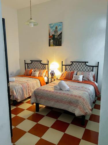 a bedroom with two beds and a checkered floor at Casona Albarelo in Puebla