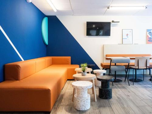 an orange couch in a room with tables and chairs at Ibis budget Béziers Est Mediterranée A9 / A75 in Béziers
