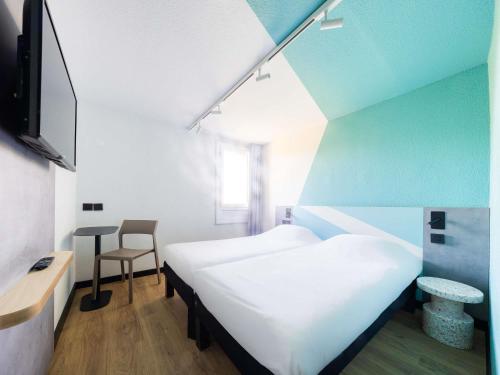 a room with two beds and a table and a chair at Ibis budget Béziers Est Mediterranée A9 / A75 in Béziers