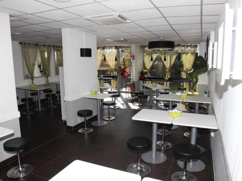 a restaurant with tables and stools in a room at Hotel Ibis Budget Nice Palais Nikaia in Nice