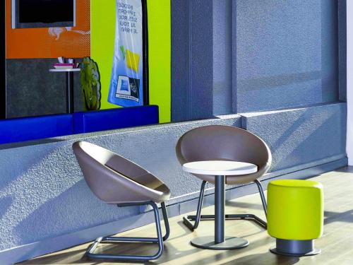 two chairs and a stool in a room at ibis budget Bordeaux Lac in Bordeaux