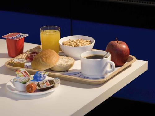 a tray of breakfast food with an apple and a cup of coffee at ibis budget Bordeaux Lac in Bordeaux