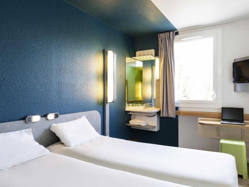 a bedroom with two beds and a window and a television at ibis budget Paris Porte de Vincennes in Paris
