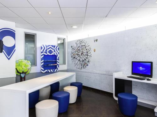 an office with blue stools and a desk with a computer at ibis budget Paris Porte de Vincennes in Paris