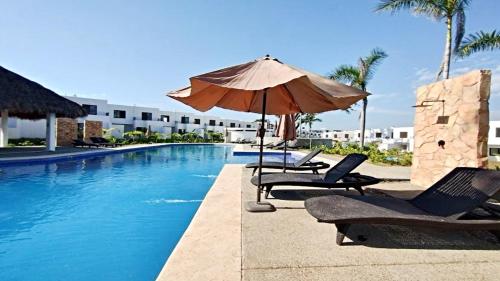 a swimming pool with chairs and an umbrella next to a hotel at Brand New Cow House Aldea Hortus 136 by Kivoya in Naranjo
