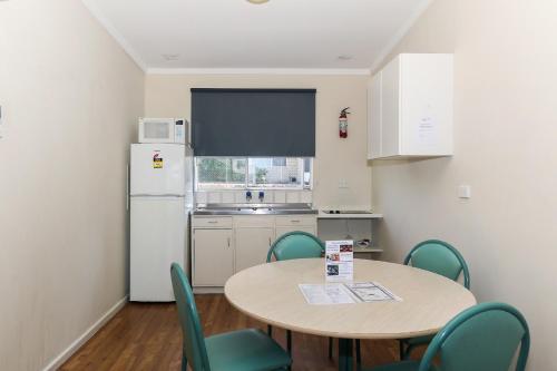 a kitchen with a table and chairs and a refrigerator at Scarborough Apartments in Perth