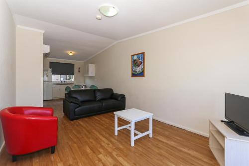 uma sala de estar com um sofá preto e uma cadeira vermelha em Scarborough Apartments em Perth