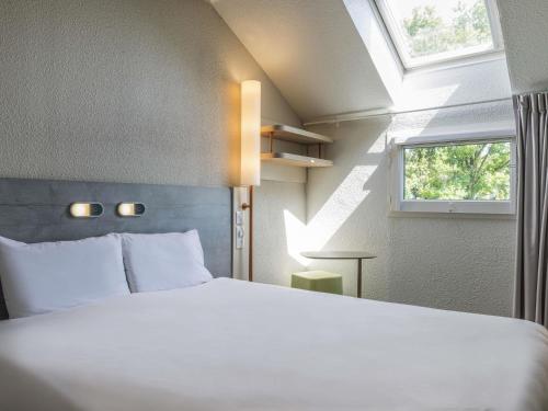 a bedroom with a large white bed and a window at ibis budget Senlis in Senlis