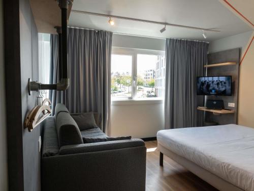 a bedroom with a bed and a couch and a window at Ibis Budget Saint Malo Centre in Saint Malo
