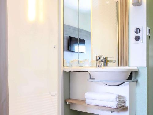 a bathroom with a sink and a mirror at Hotel Ibis Budget Abbeville in Abbeville